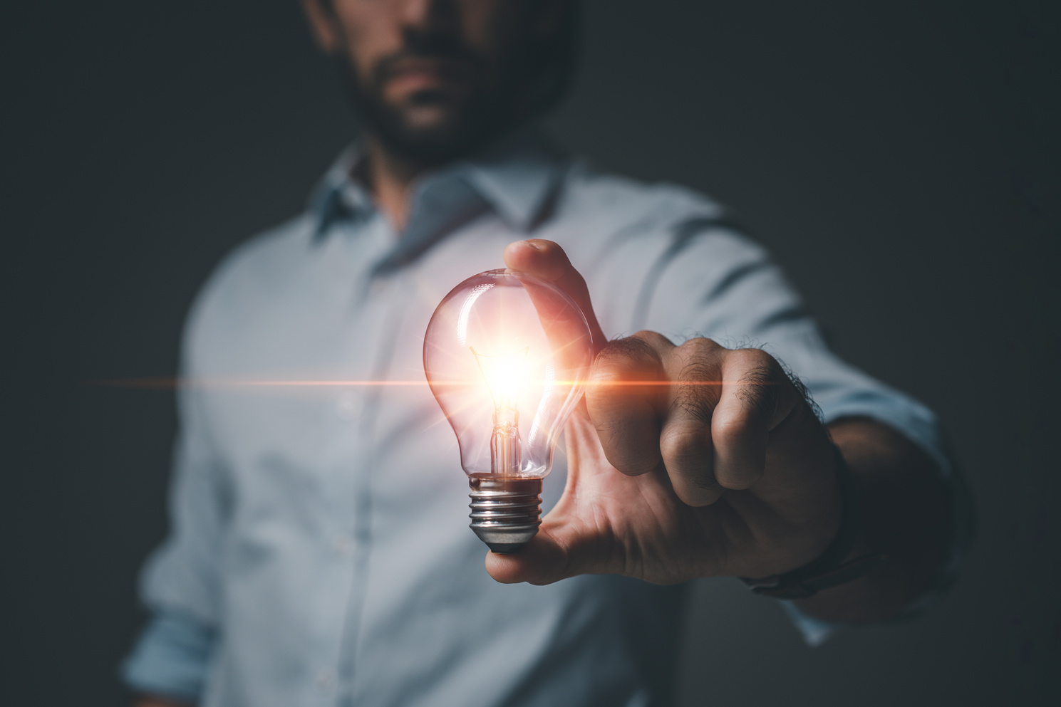 Hand of Man holding light bulb on dark blackground. Idea innovation and creativity concept. Innovative technology and business development